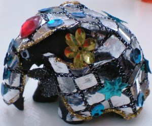 Elephant covered in small mirrors and flowers